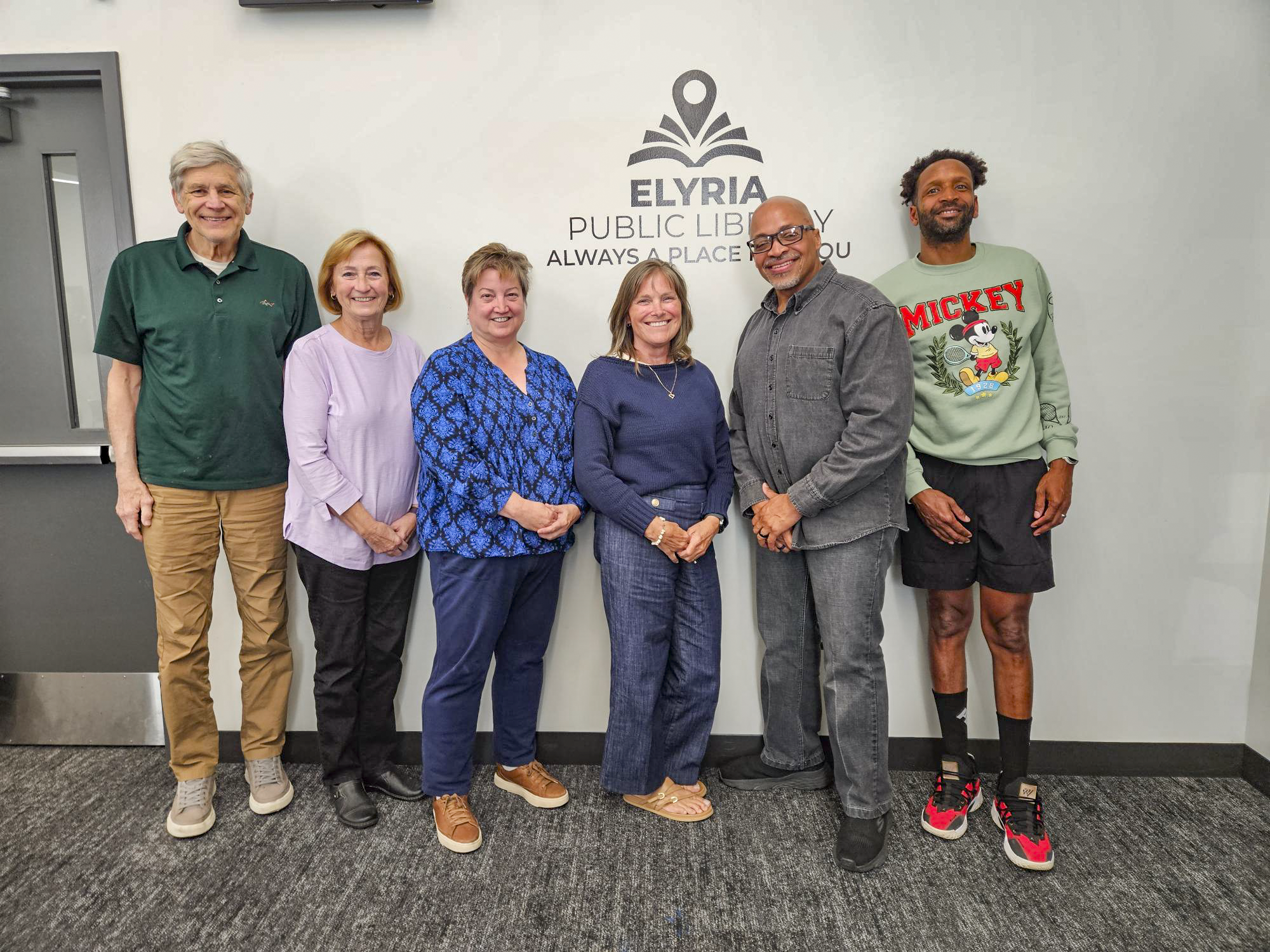A photo of 6 board members standing in a line against a wall.